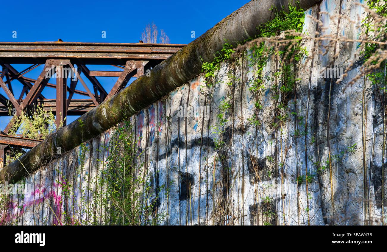 Parte rimanente del muro di Berlino con graffiti e storica struttura in acciaio sullo sfondo. Berliner Mauer, Germania. Foto Stock