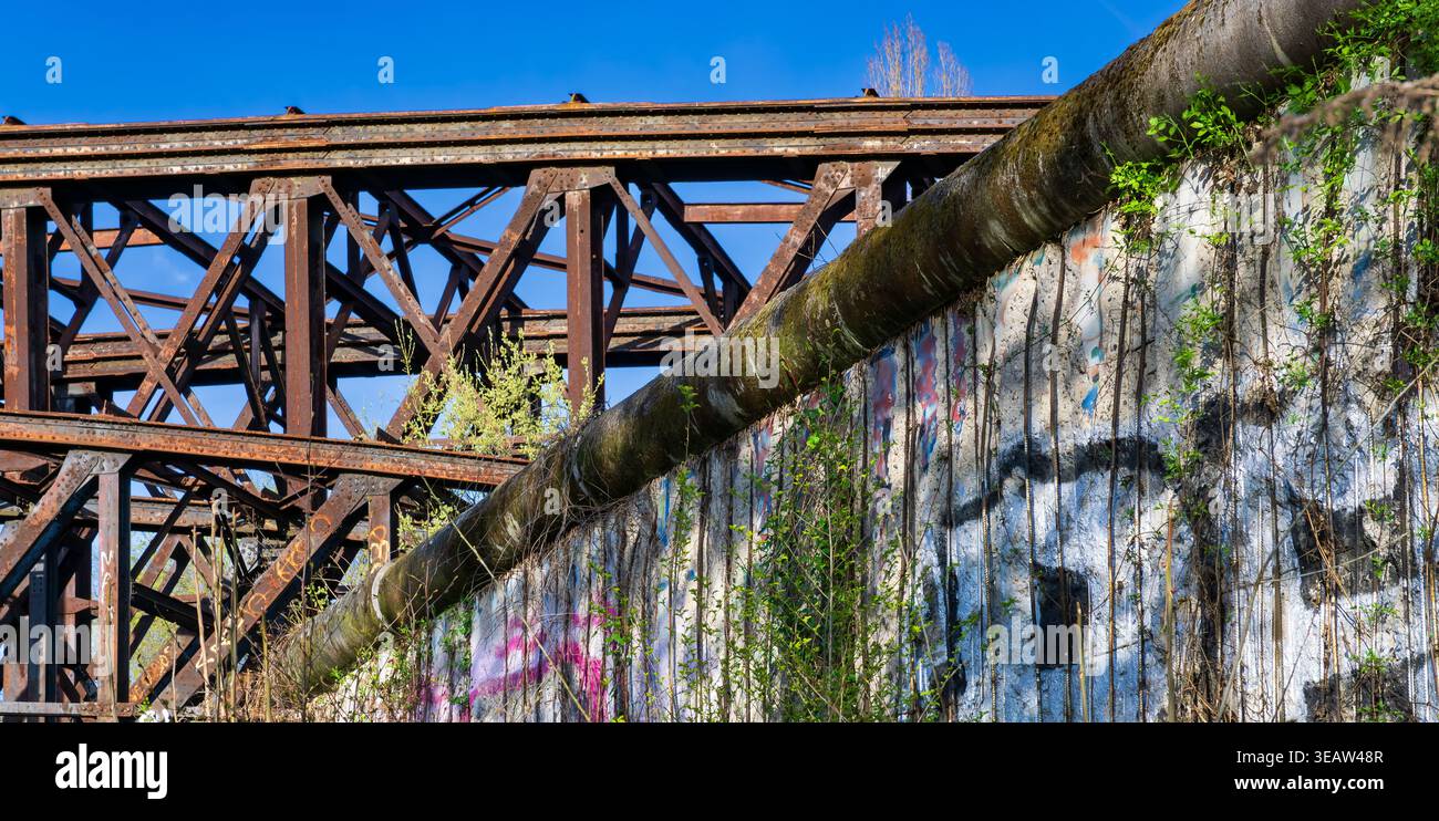 Parte rimanente del muro di Berlino con graffiti e storica struttura in acciaio sullo sfondo. Berliner Mauer, Germania. Foto Stock