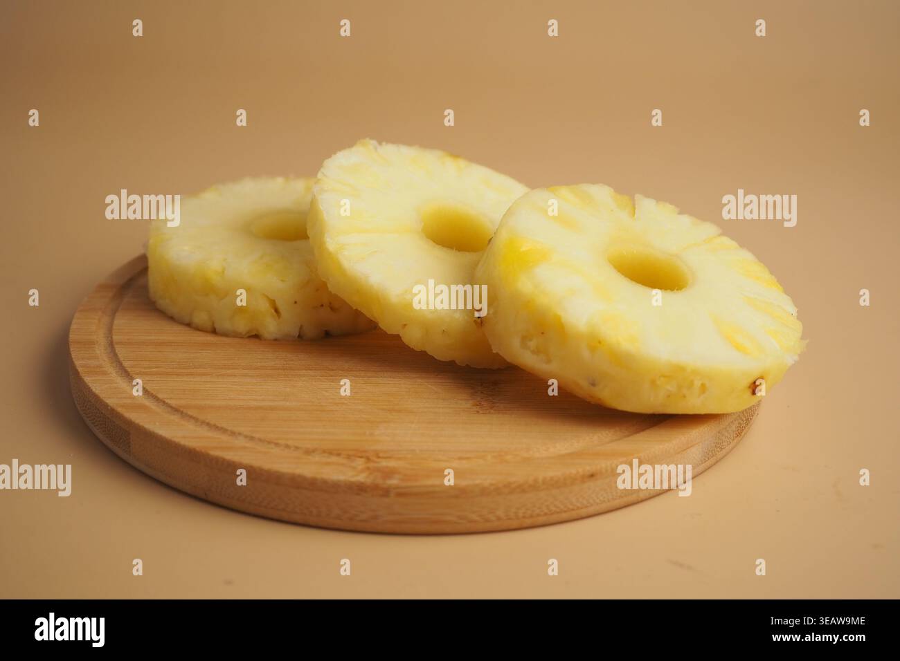 Affettare l'ananas su un asse di legno in piena luce Foto Stock