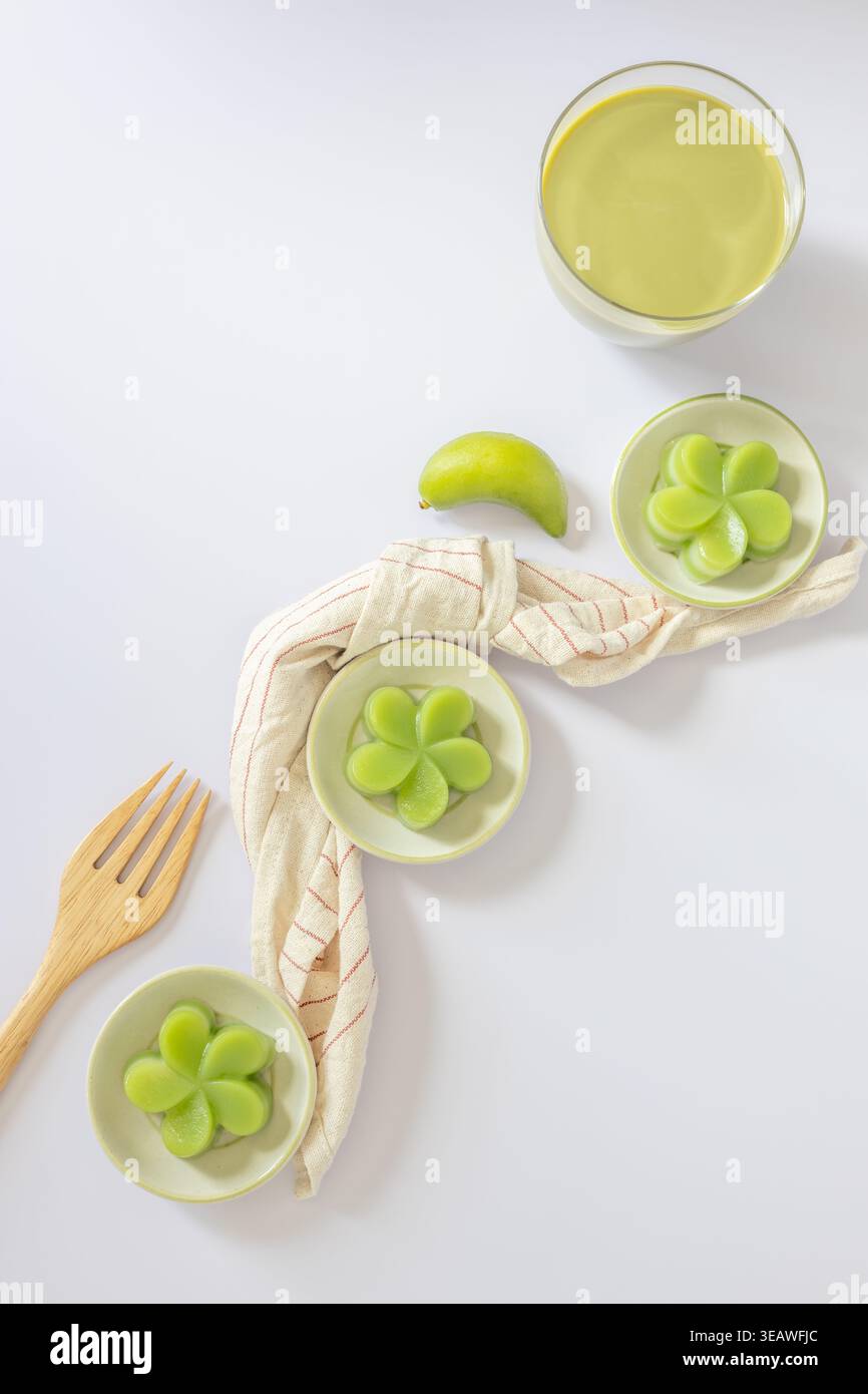 Vista dall'alto di una torta di panda verde al vapore su piccole tazze, servita con una tazza di tè verde, un tradizionale dessert tailandese. Primo piano. Posizione piatta. Foto Stock
