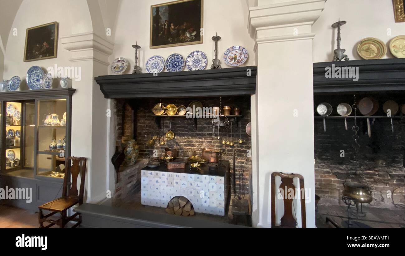 Interno di una cucina storica a Palazzo Rundāle, Lettonia, con grandi caminetti, pentole antiche in rame, piatti in ceramica, e cucina tradizionale Foto Stock