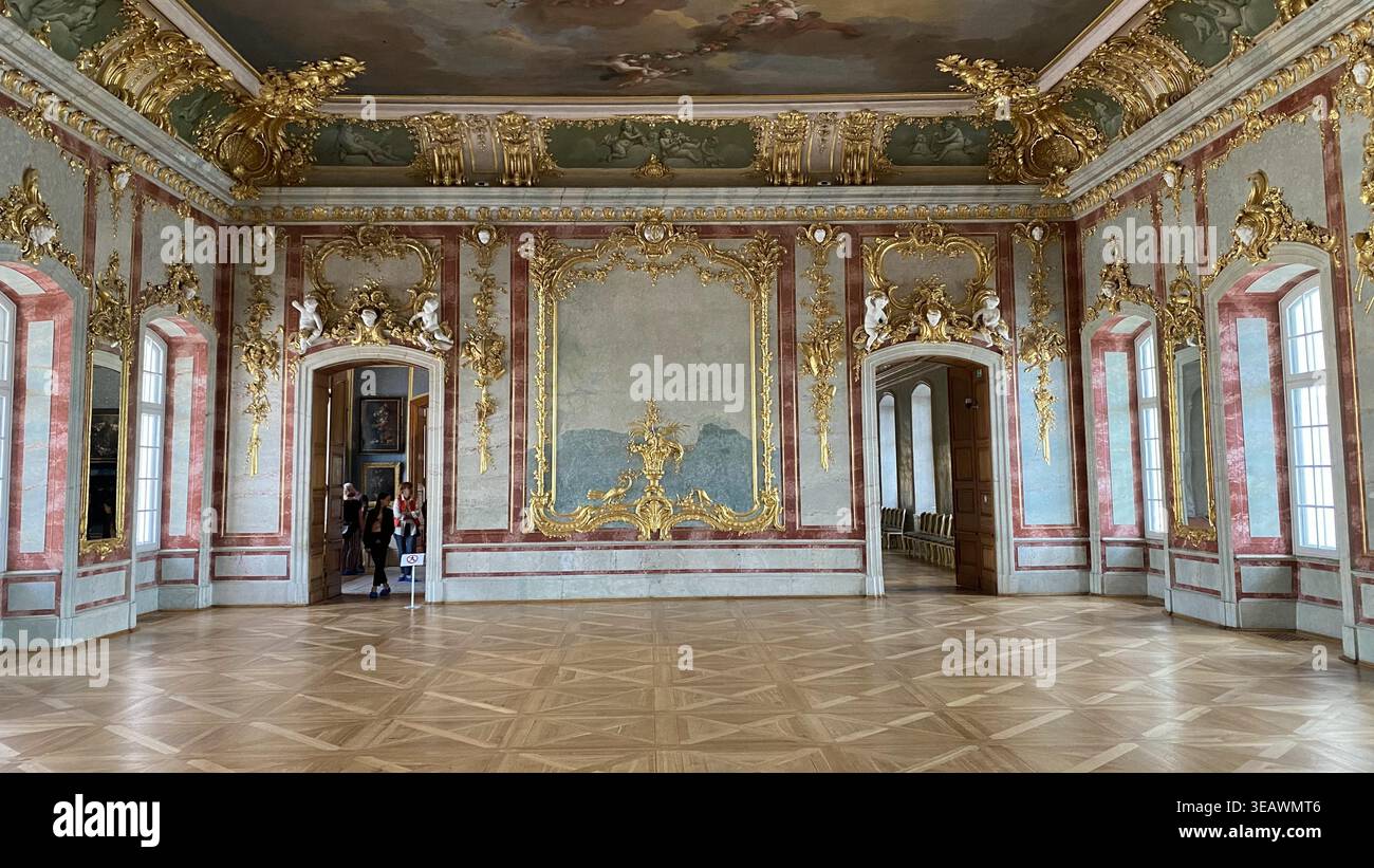 Lussuosa sala interna barocca nel Palazzo Rundāle, Lettonia, caratterizzata da elaborate decorazioni murali dorate, dettagli in stucco, soffitto dipinto e parquet Foto Stock