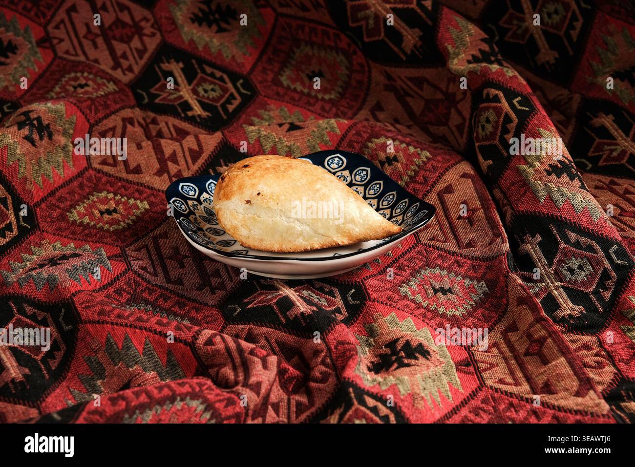 Snack decorativi in un ambiente accogliente. Empanada artigianale su tappeto decorativo Foto Stock