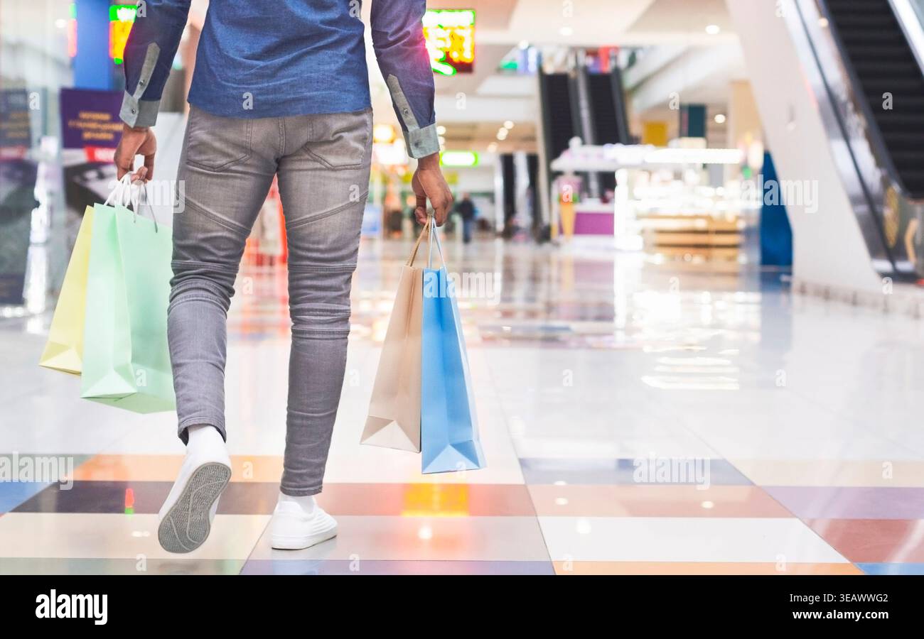 Uomo africano irriconoscibile con borse per lo shopping nel centro commerciale Foto Stock