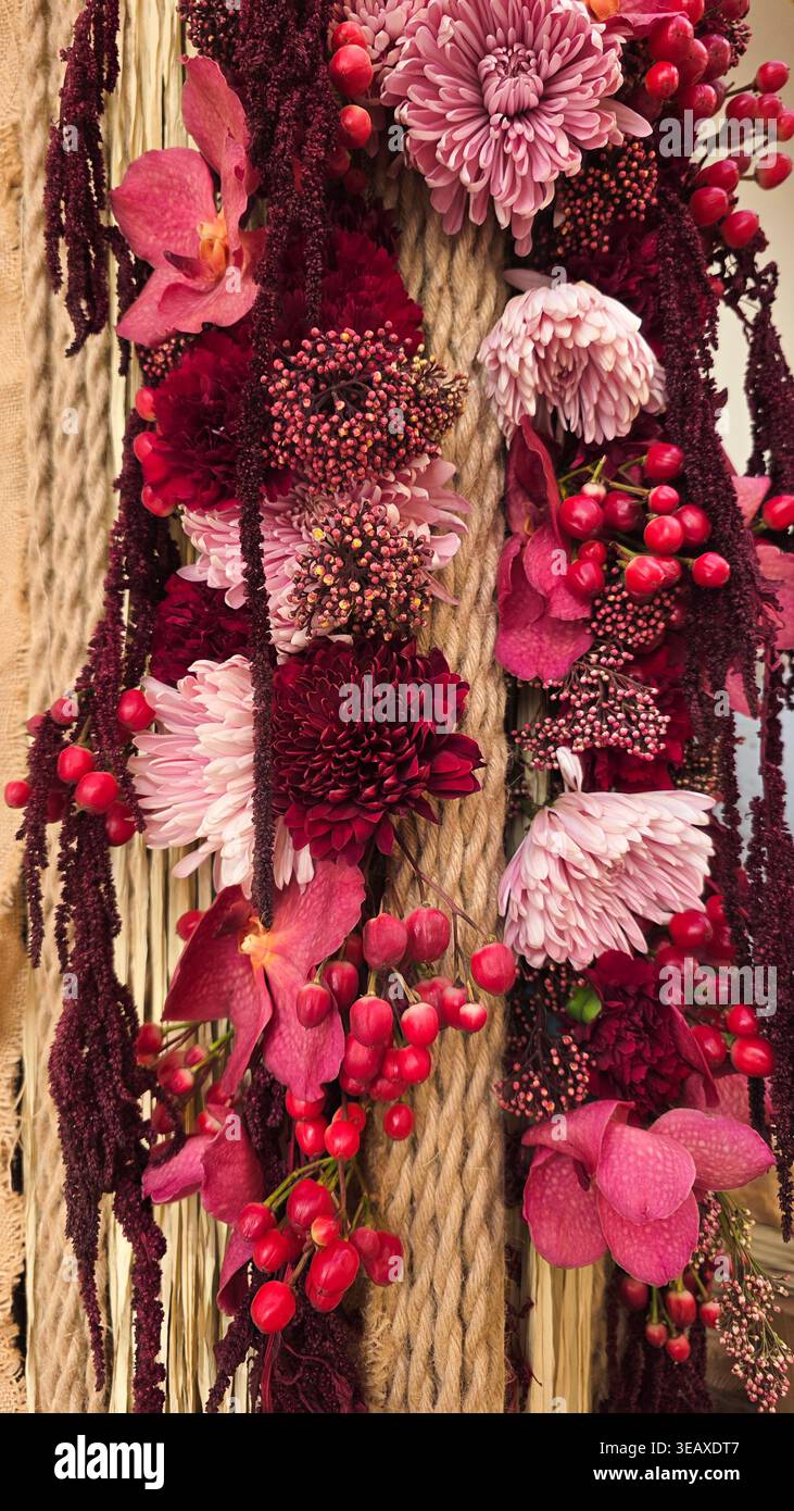 Un primo piano di una disposizione floreale in sfumature di marrone e rosa su uno sfondo di corda. - Immagine stock catturata con smartphone