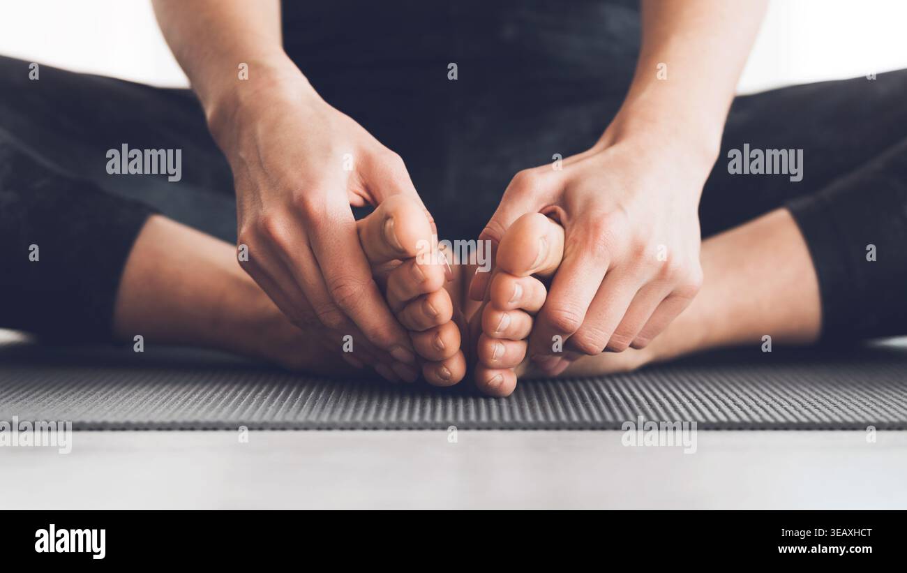 Il praticante di yoga si allunga e si rilassa in un tranquillo ambiente interno durante la sessione di pratica mattutina Foto Stock