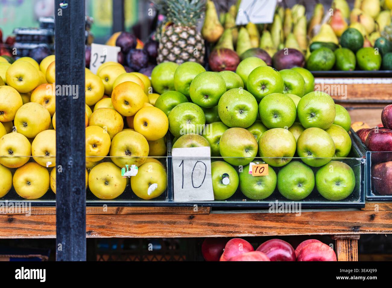 Mercato della frutta di Batumi con mele verdi e gialle fresche e frutta assortita, come ananas e prugne, sotto la luce naturale Foto Stock