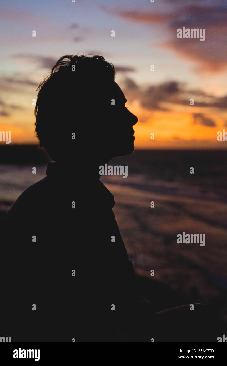 Silhouette ravvicinata di una persona di profilo al tramonto sull'oceano, Bali Foto Stock