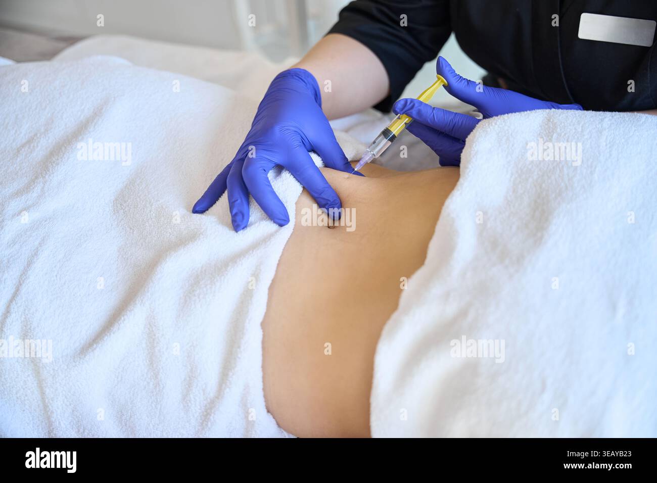 Il medico fa l'iniezione di gas di ozono nell'addome femminile su un lato della terapia con ozono Foto Stock