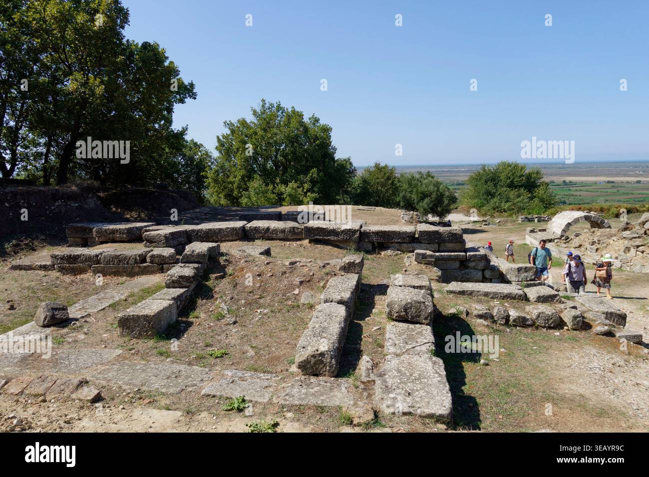 Antiche fondamenta in pietra e rovine del Parco Archeologico di Apollonia, con i turisti che esplorano il monumento storico sotto un cielo azzurro Foto Stock