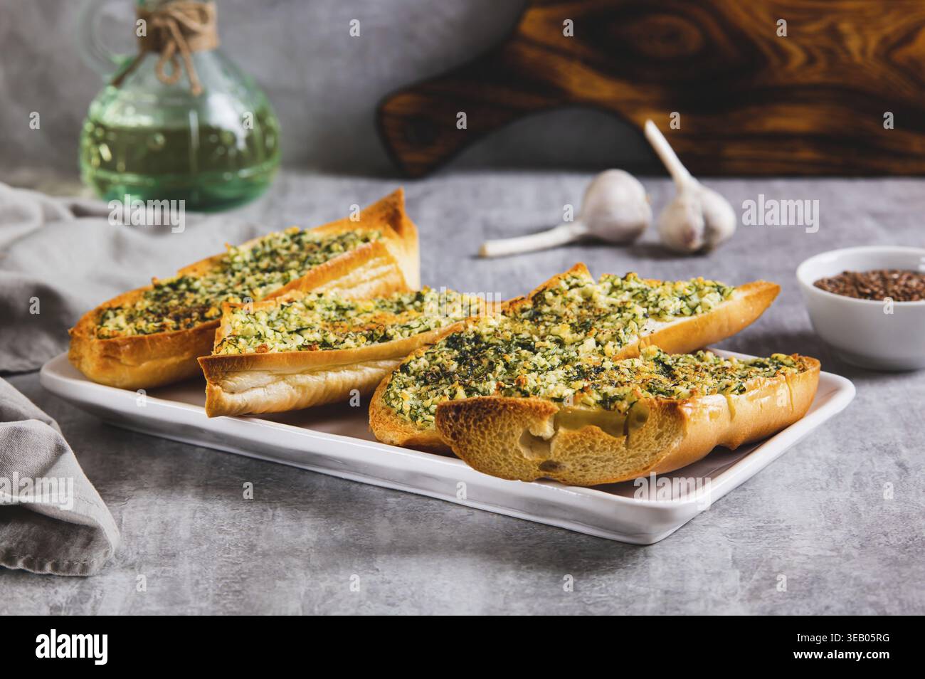 Baguette al forno con burro, aglio e aneto su un piatto sul tavolo Foto Stock