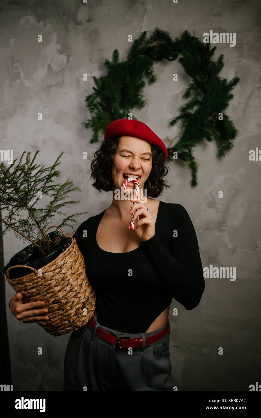 Donna che mangia Candy cane che tiene la corona di Natale Foto Stock