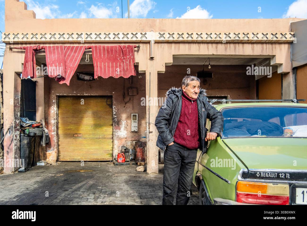 Tafroute, Marocco - 25 dicembre 2025: Un anziano con la sua vecchia auto Renault 12 davanti al garage. Foto Stock