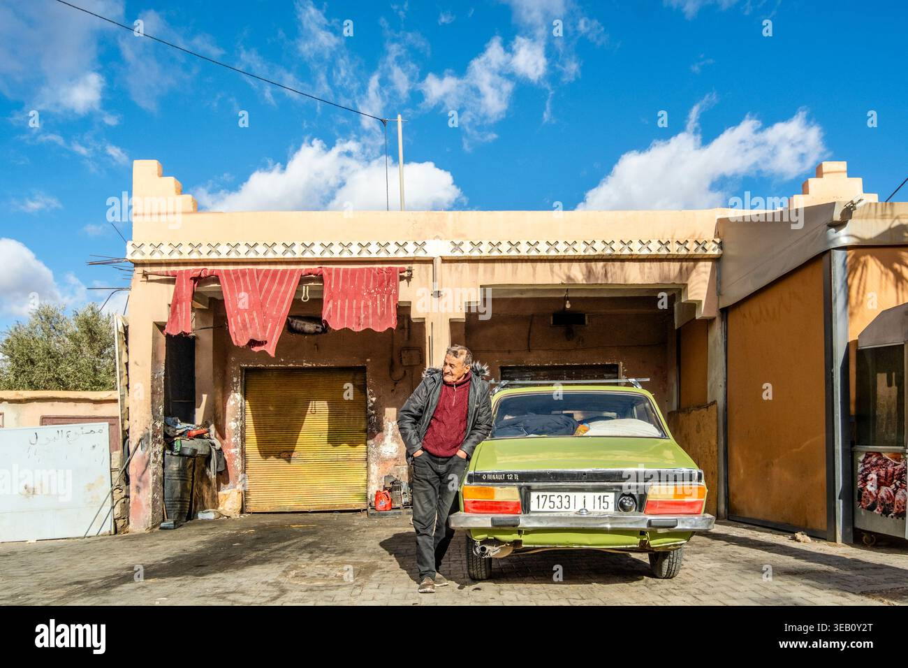Tafroute, Marocco - 25 dicembre 2025: Un anziano con la sua vecchia auto Renault 12 davanti al garage. Foto Stock