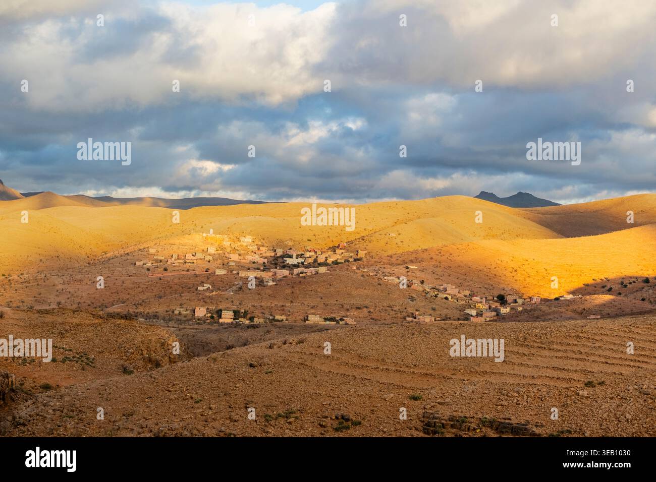 Montagne anti-Atlante, grandi montagne nella regione. Al centro delle altezze, sullo sfondo appare un piccolo villaggio, un cielo blu e alcune nuvole Foto Stock