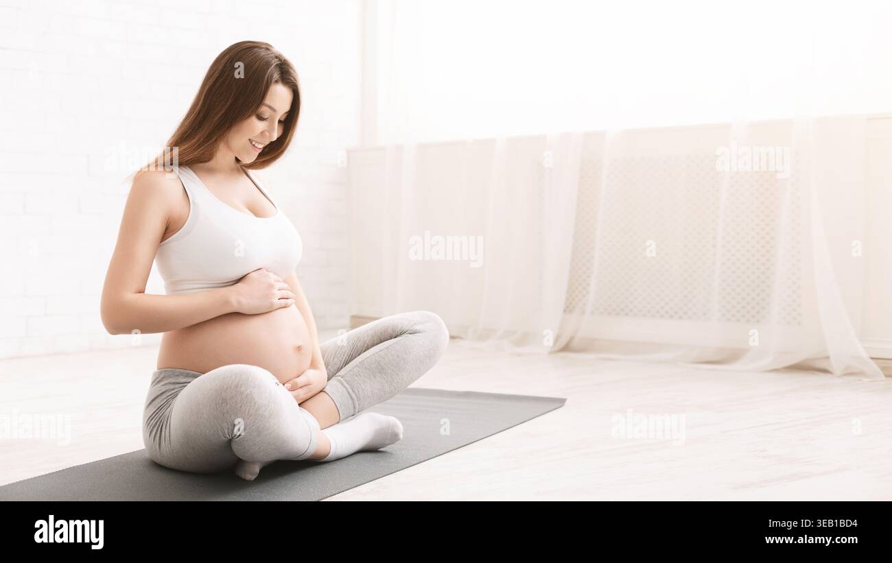 Attiva donna incinta seduta sul pavimento dopo facendo sport Foto Stock
