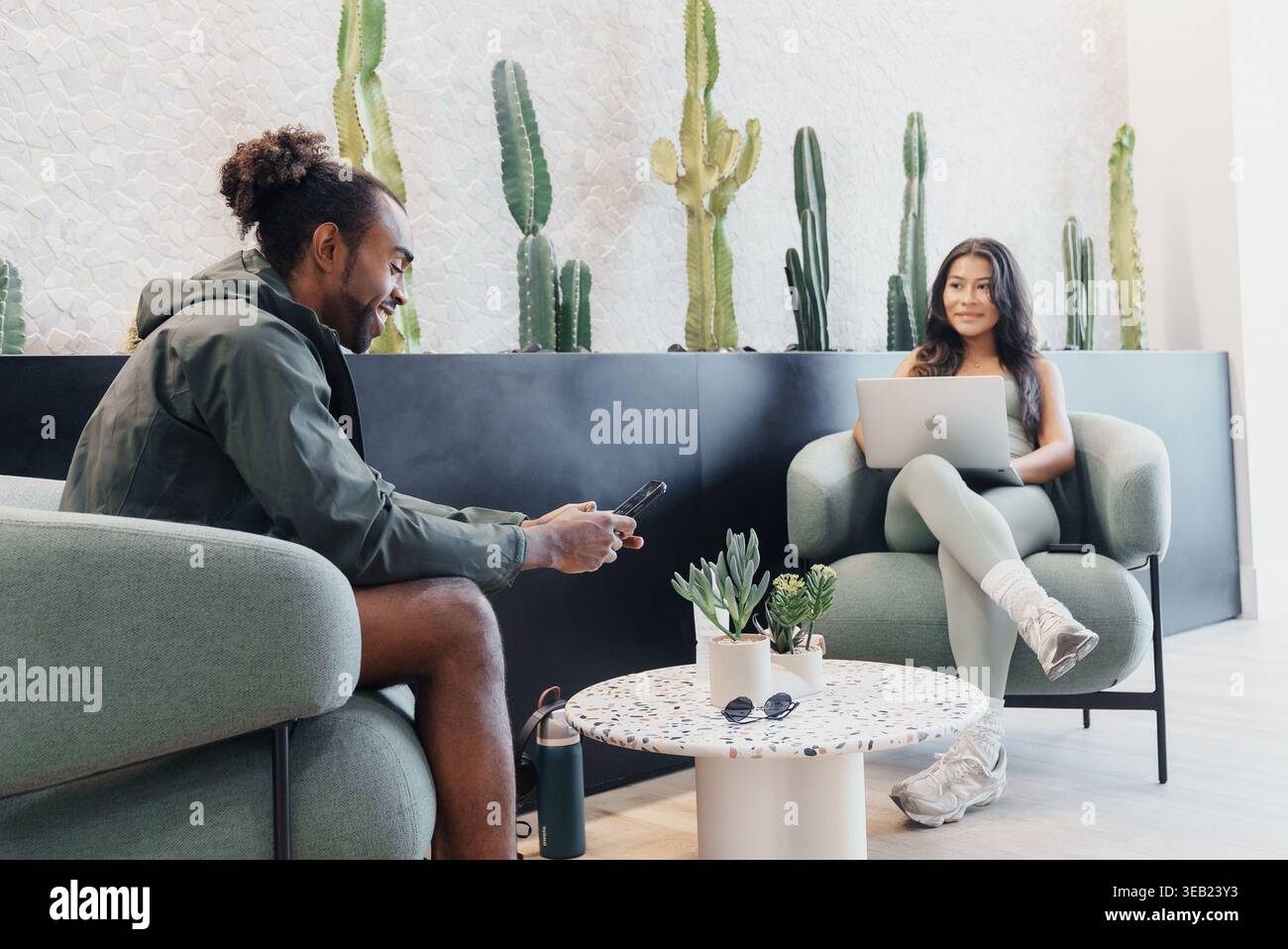 Conversazione informale di mentoring. Due persone si sono impegnate in un dialogo rilassato nelle piante vicine. Scambio laidback tra due persone circondate dallo stabilimento Foto Stock