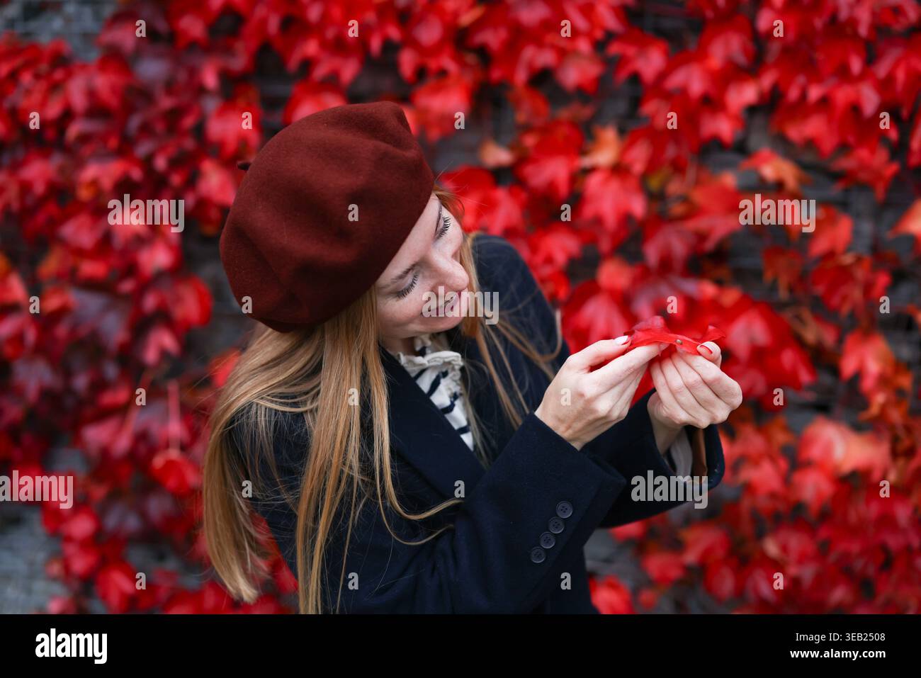Donna sorridente che posa con le mani sul viso, colori autunnali e eмоtions positivo. Foto Stock