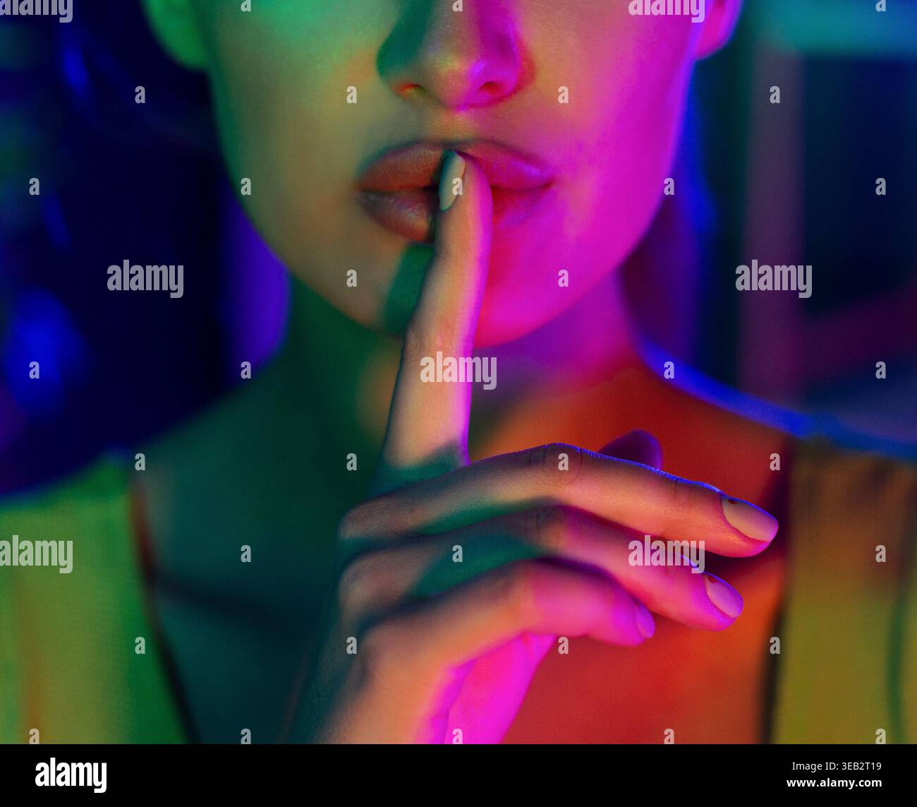 Donna che gestiva il silenzio in un ambiente illuminato al neon Foto Stock