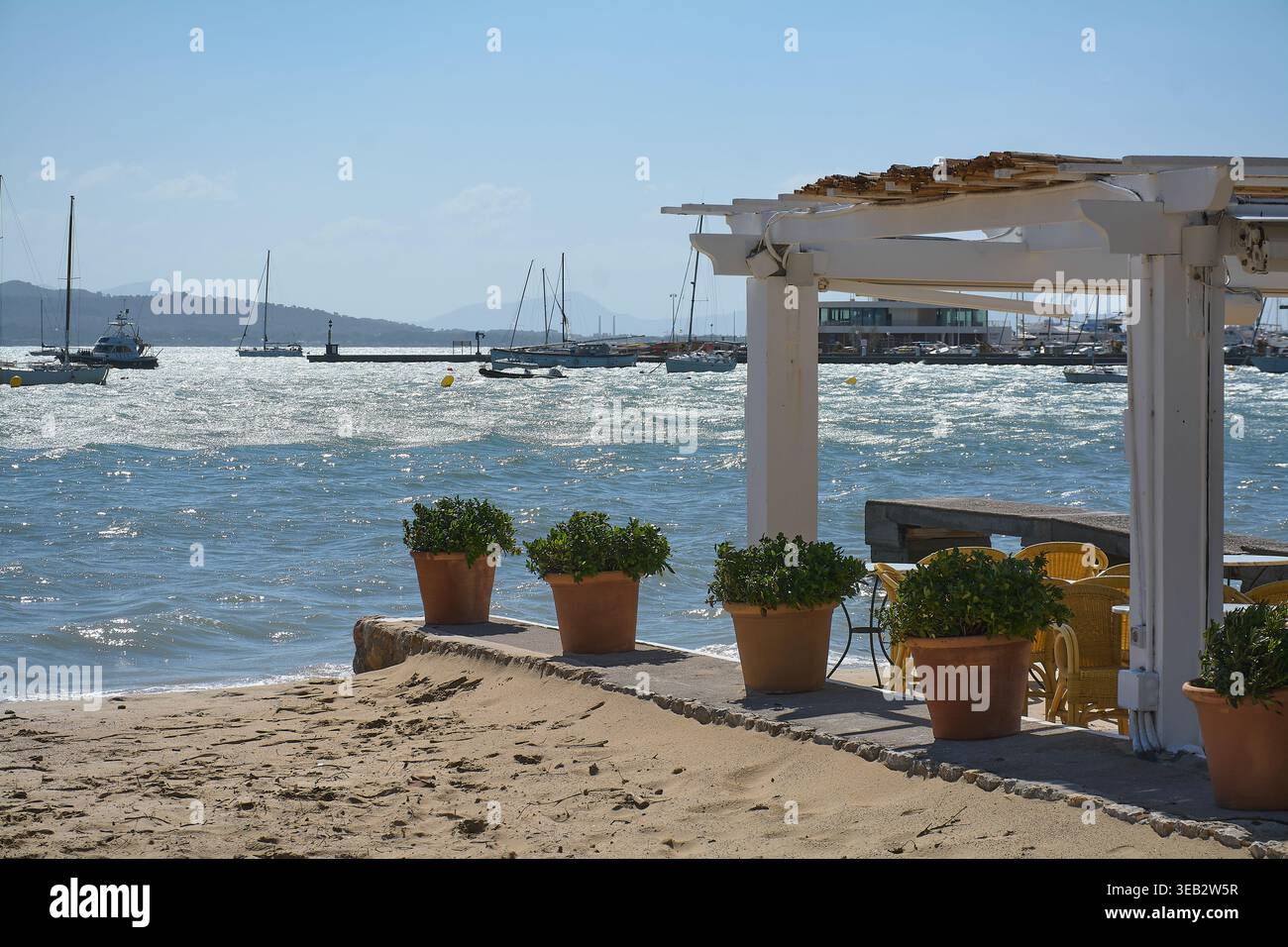 Maiorca Spagna - 24 aprile 2026: Soleggiata vista costiera del porto di Port de Pollenca con yacht di lusso e barche a vela ancorate nel turchese Mediterraneo Foto Stock