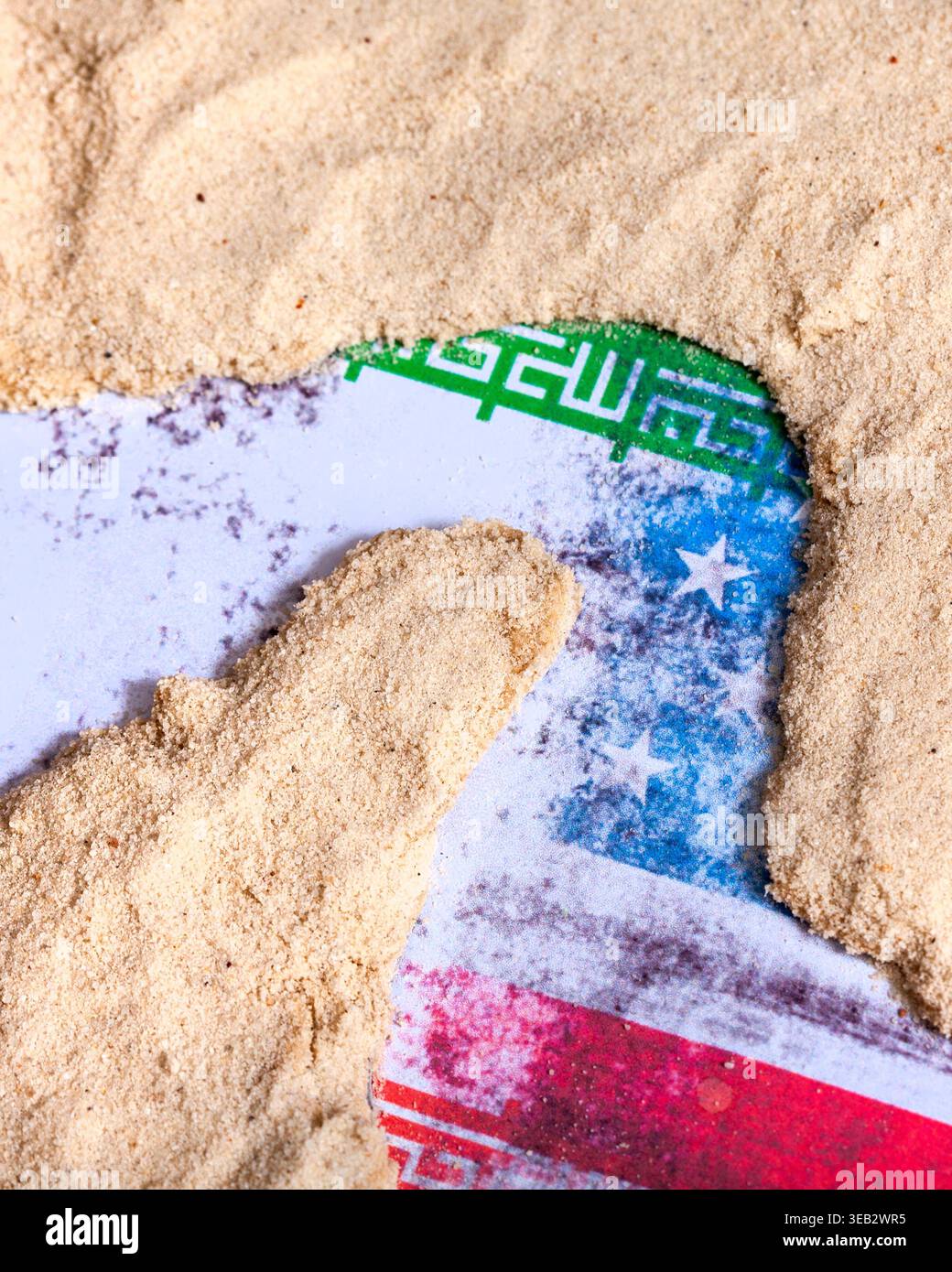 Immagine concettuale che mostra bandiere globali parzialmente sepolte sotto la sabbia, che rappresenta come i disagi nello stretto di Hormuz influenzano più nazioni. Alto Foto Stock