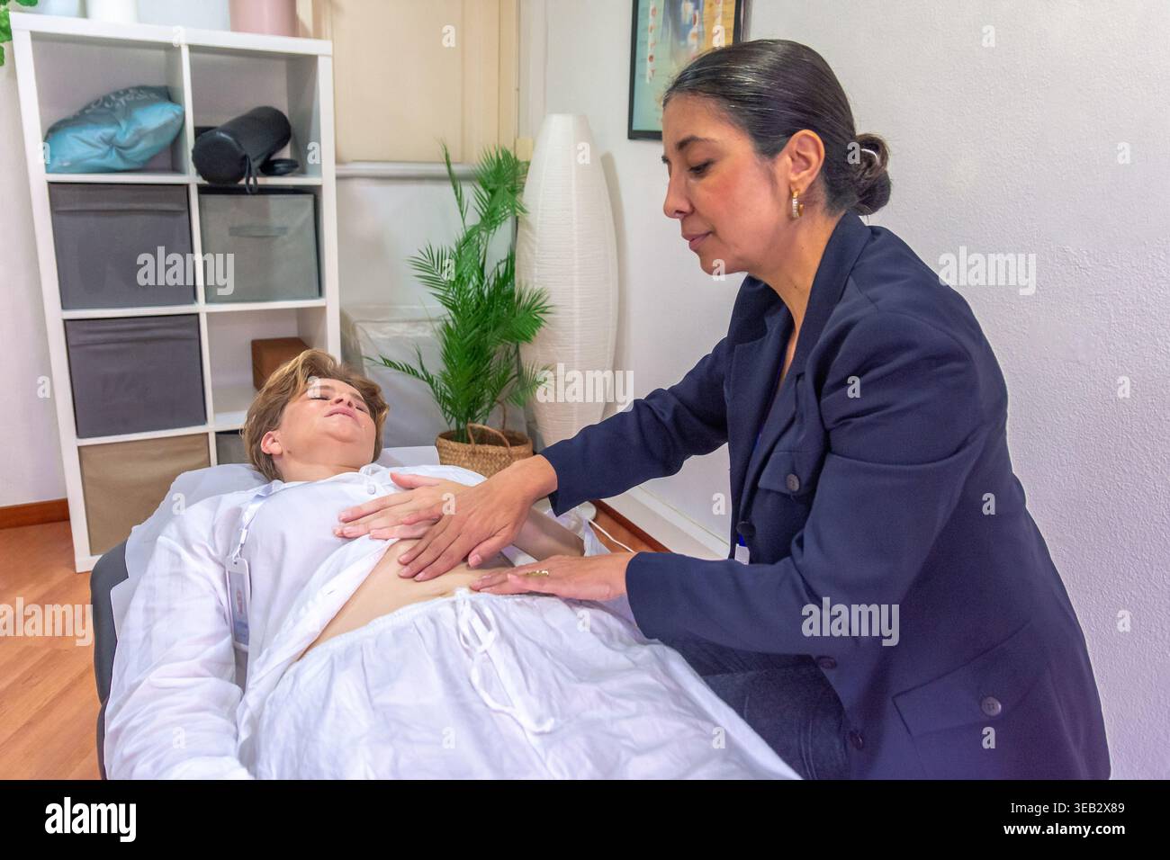 Praticante che esegue la guarigione energetica reiki sul corpo del cliente Foto Stock