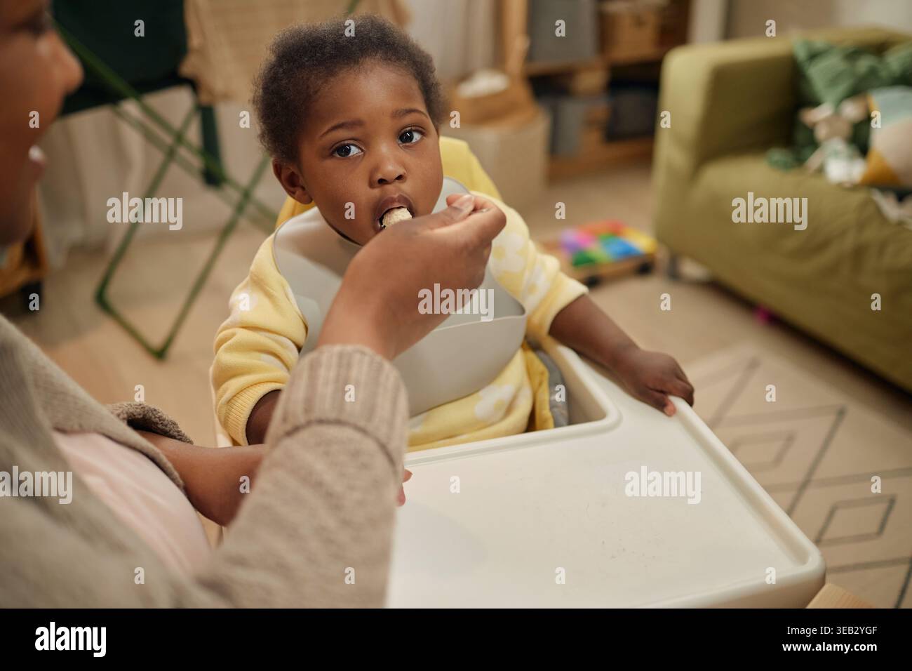 Bimbo nero che mangia mentre la mamma dà da mangiare a casa con budget limitato Foto Stock