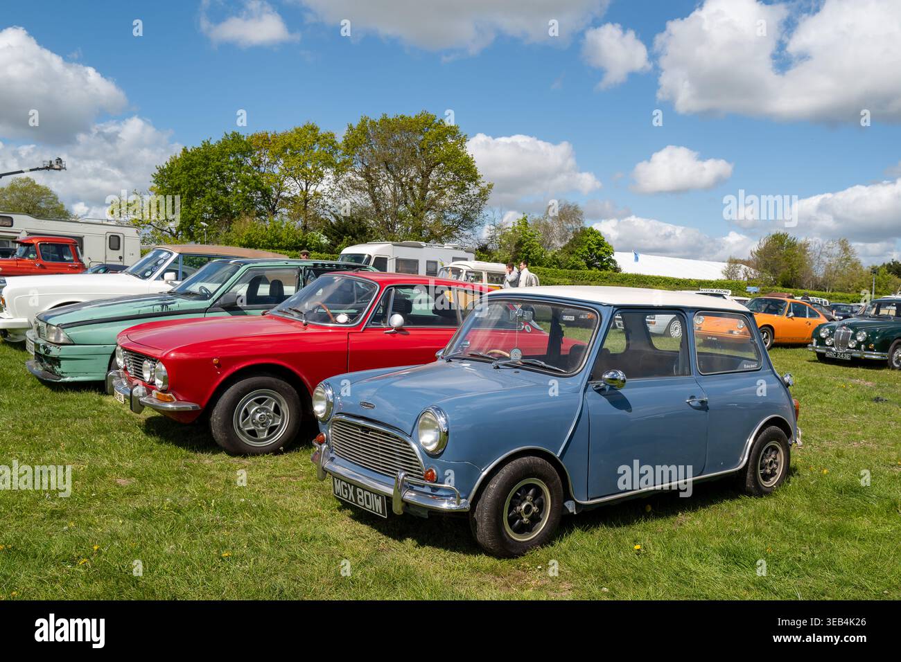 Aprile 2026 - Una Mini Cooper blu parcheggiata davanti all'Alfa Romeo Giulietta rossa nel parcheggio auto d'epoca sul circuito Goodwood Race, West Sussex, Inghilterra, Regno Unito Foto Stock