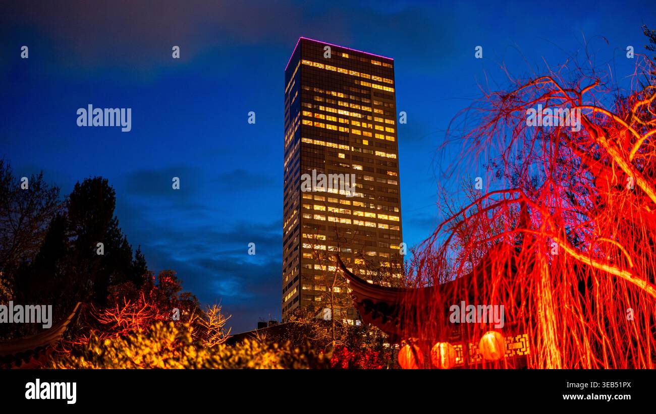 Vista notturna del grattacielo illuminato della U.S. Bancorp Tower incorniciato da un'architettura tradizionale e da alberi rossi lucenti nel giardino cinese LAN su Foto Stock