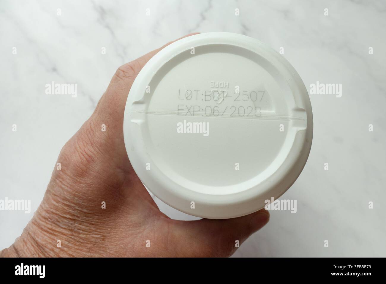 Vista inferiore del contenitore in polvere proteica con numero di lotto e data di scadenza a portata di mano Foto Stock