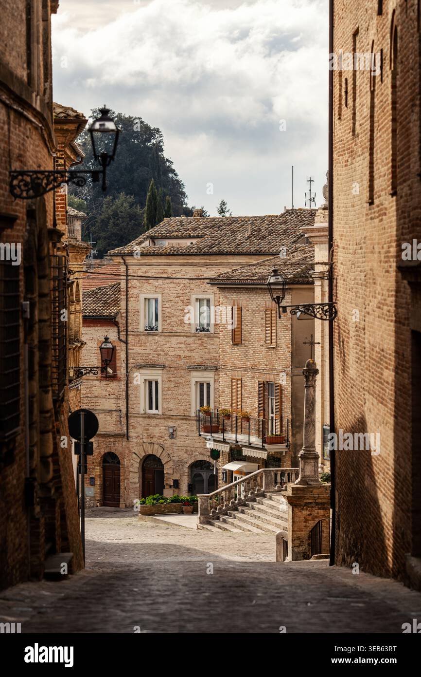 Vista della storica architettura in mattoni e delle strette stradine acciottolate della città vecchia sotto un cielo nuvoloso a Ripatransone, Marche, Italia. Foto Stock