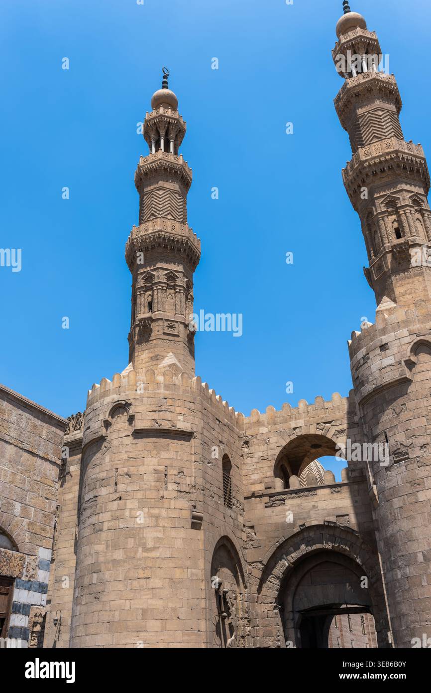 Vista di Bab Zuwayla, la storica porta medievale con i suoi due torreggianti minareti ornati e le massicce pareti di pietra sotto un cielo azzurro e limpido El-DARB El-Ahmar, Foto Stock