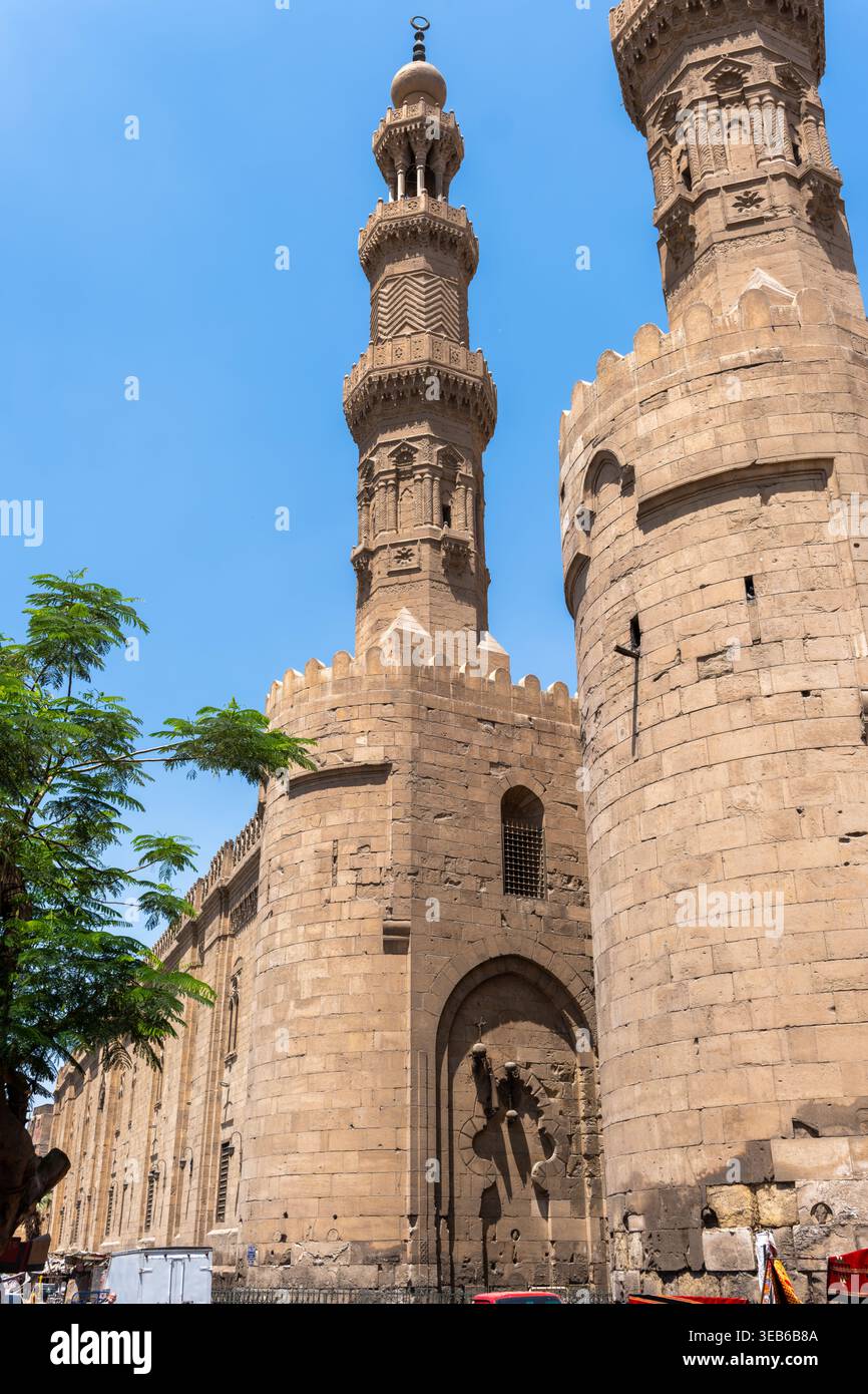 Vista della storica porta Bab Zuwayla e del suo minareto in pietra ornato con intricate incisioni sotto un cielo azzurro a El-DARB El-Ahmar, il Cairo, Egitto. Foto Stock
