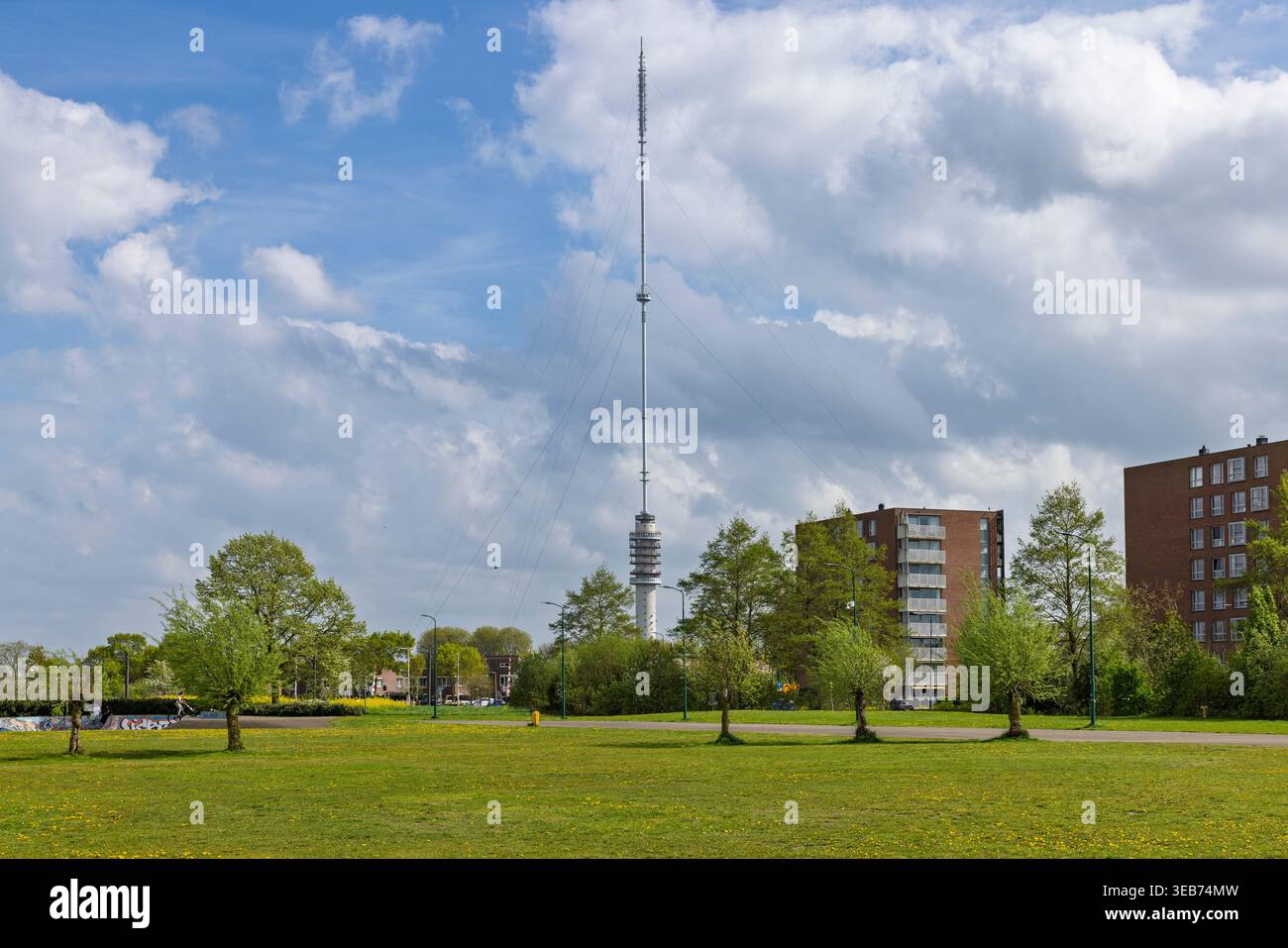 IJsselstein, Paesi Bassi, 16 aprile 2026. L'imponente trasmettitore della Gerbrandy Tower si erge su un parco pubblico verde con fiori primaverili gialli. Foto Stock