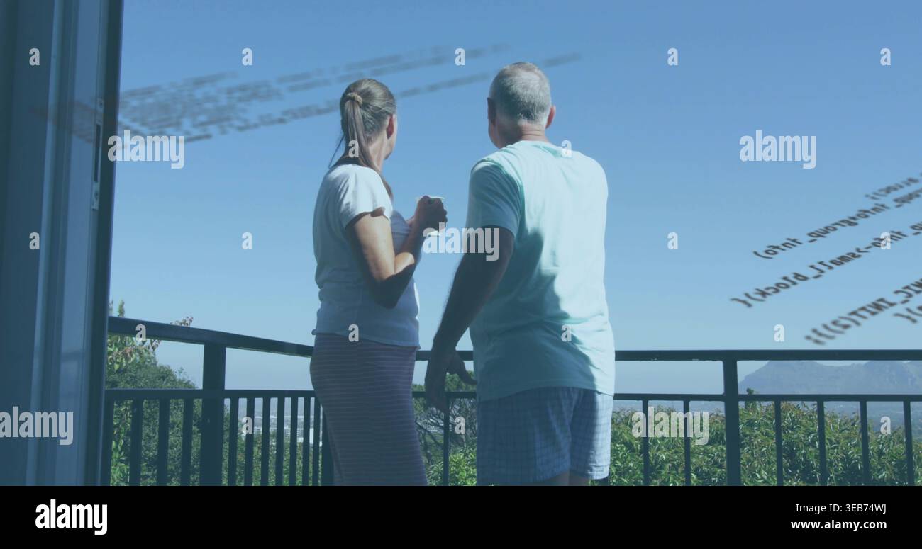 Coppia senior in piedi in abbigliamento casual che guarda le colline sul balcone di casa tenendo la tazza, riflesso del codice Foto Stock