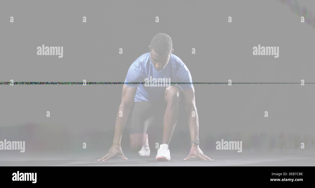 Atleta che accovaccia si prepara a fare uno sprint in studio, indossando camicia blu, scarpe bianche, orologio da polso Foto Stock