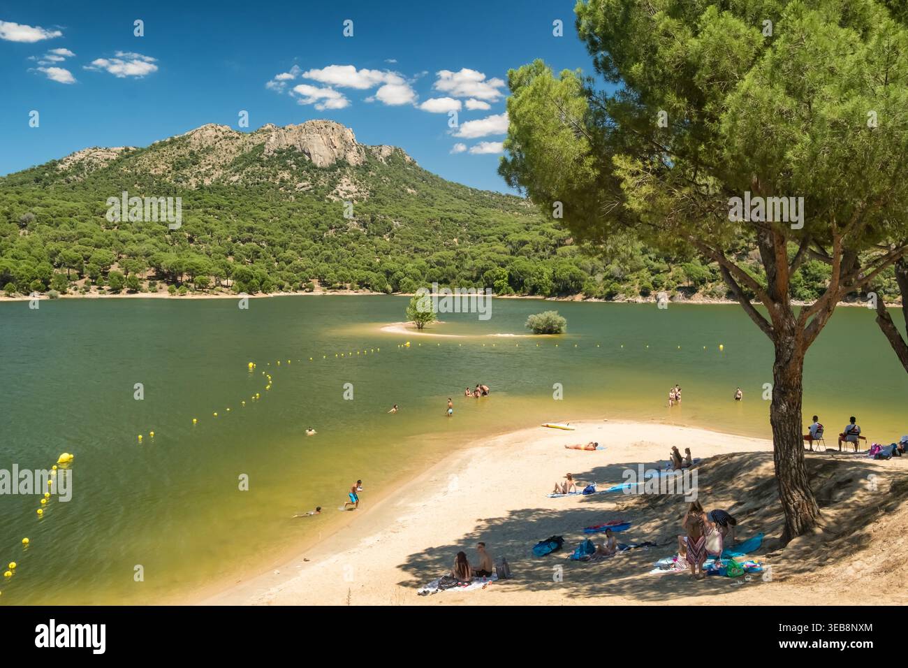 Persone che si rilassano a Sandy Beach sul lago con sfondo montano e foresta Foto Stock