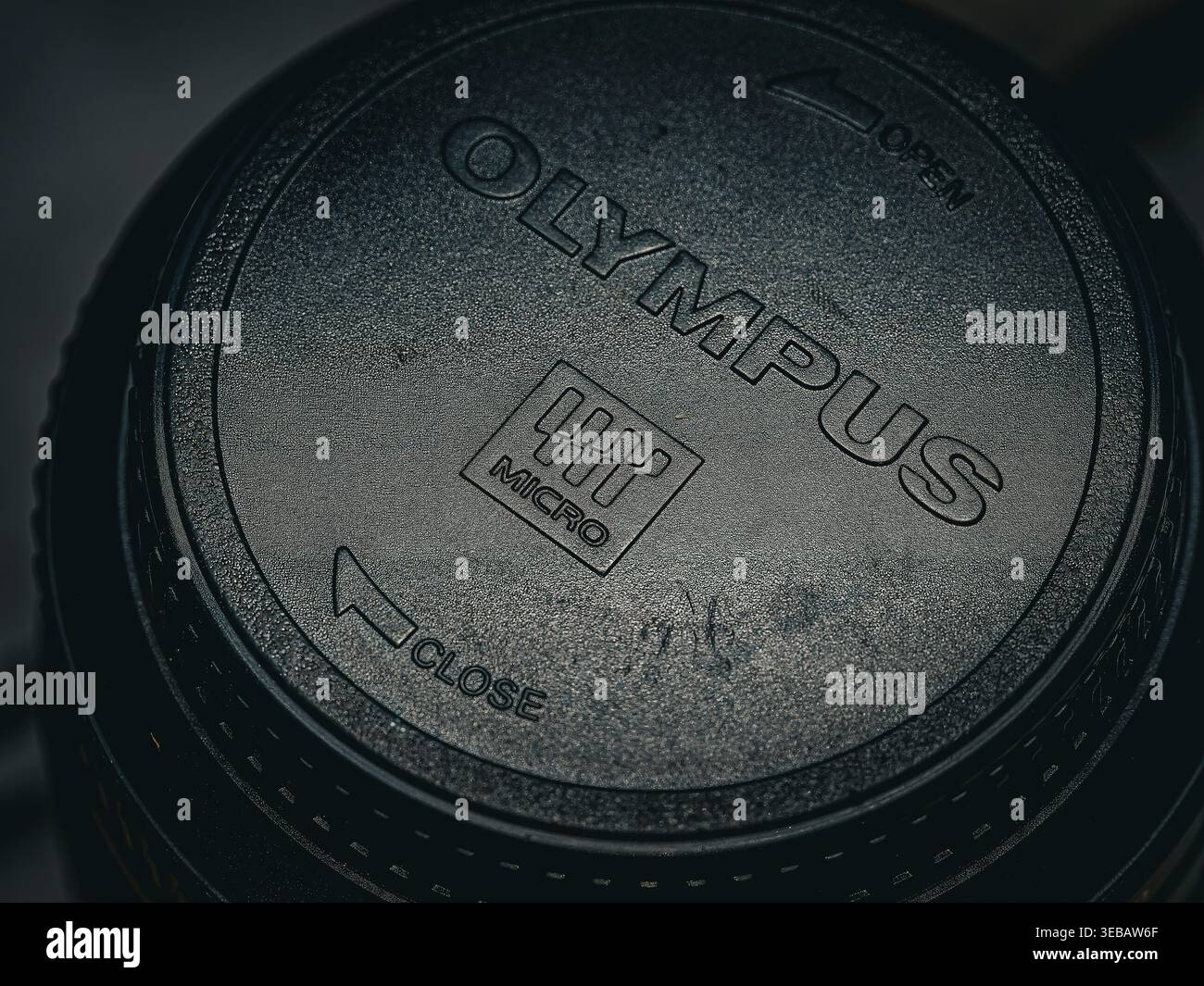 Un primo piano dettagliato top-down di un copriobiettivo Olympus Micro in plastica nera con logo e testo chiari Foto Stock