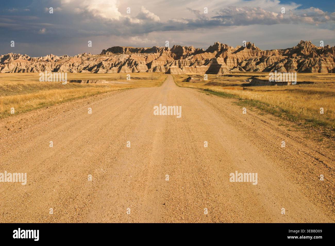 Paesaggio delle Badlands con colline e spettacolari nuvole sopra una strada sterrata che si dirige in lontananza Foto Stock
