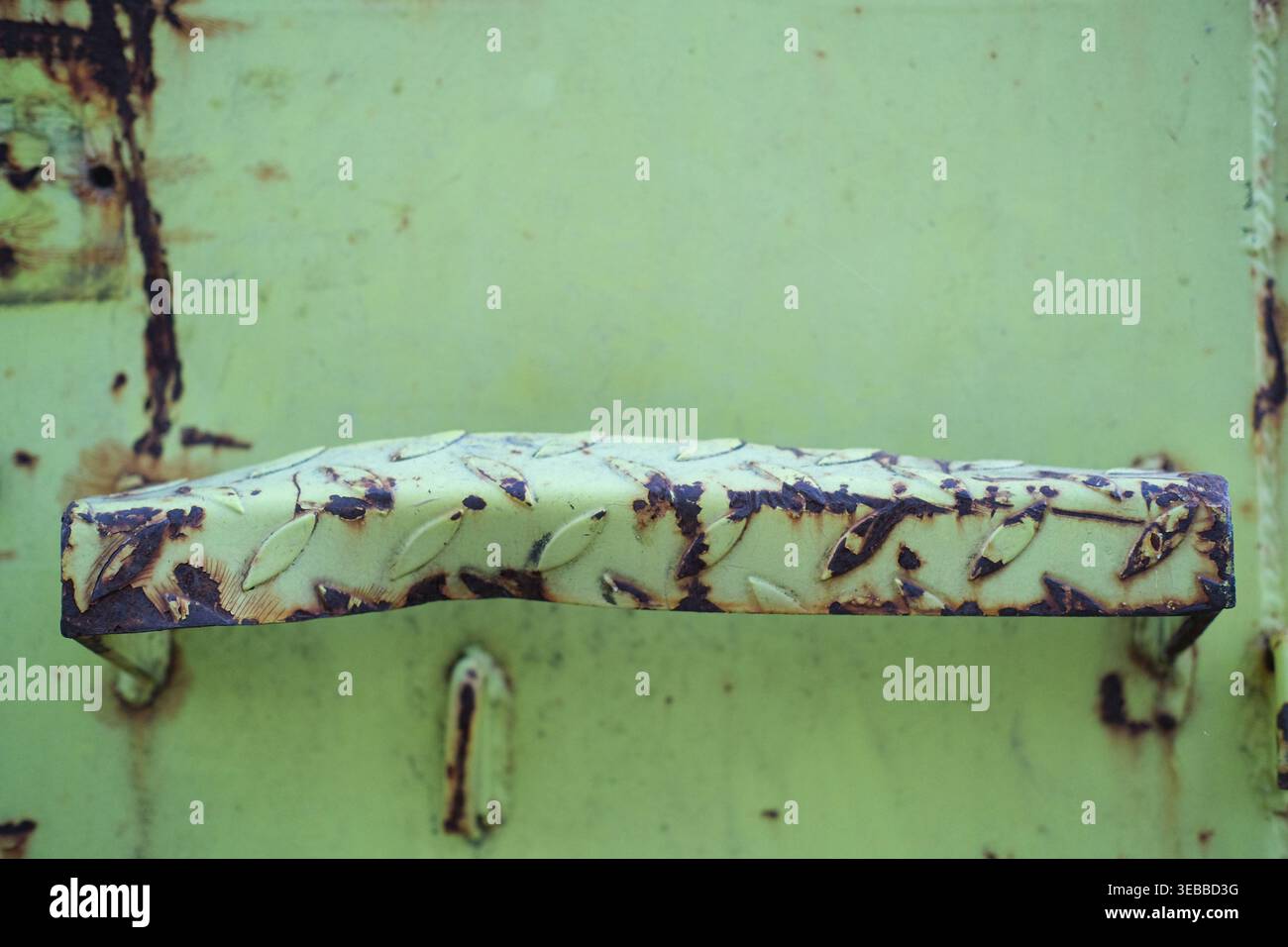 L'impugnatura in metallo arrugginito è fissata a un contenitore industriale verniciato di verde Foto Stock
