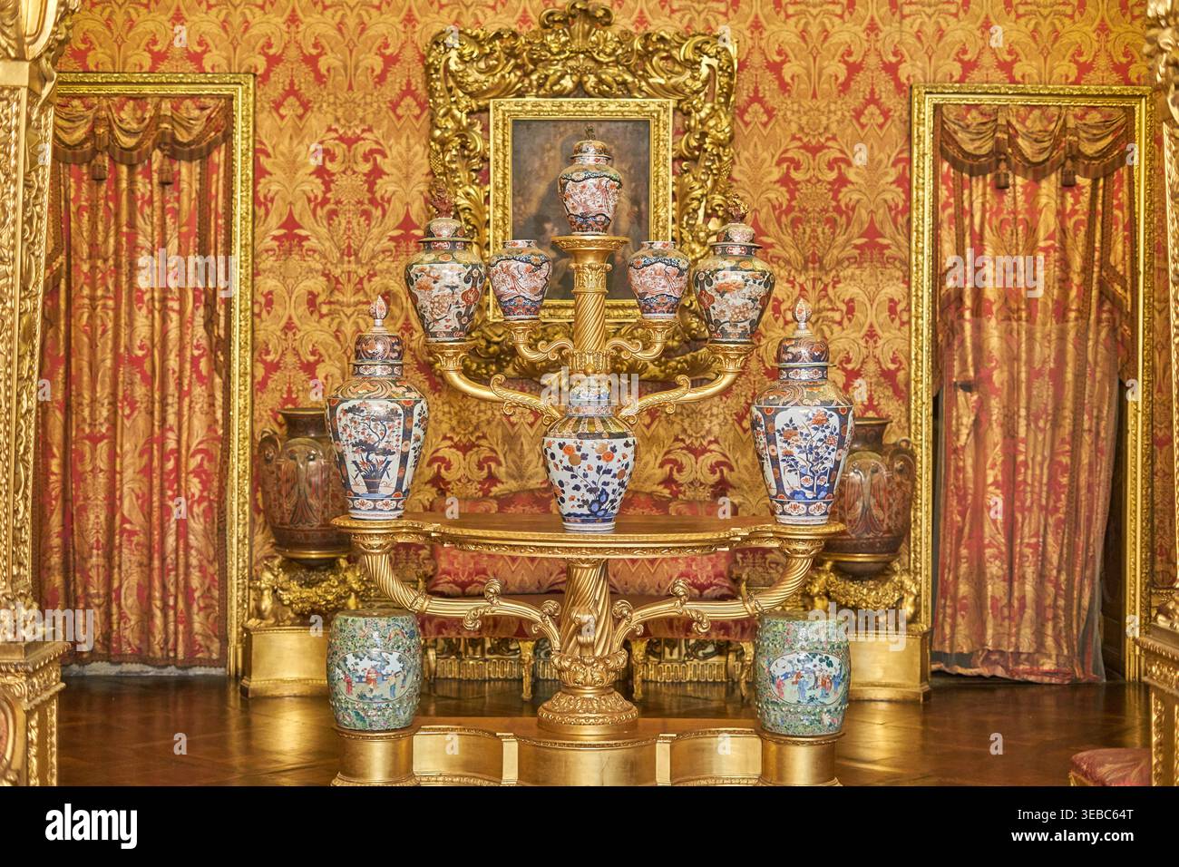 Un interno barocco sontuoso con un elaborato supporto dorato adornato da vasi in porcellana cinese antica in stile Imari, posizionato contro Foto Stock