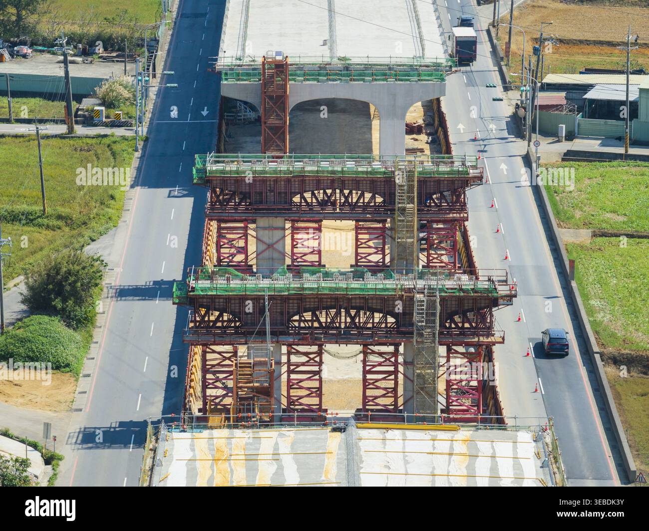Vista aerea della costruzione di autostrade sopraelevate con ponteggi in acciaio e pilastri in cemento tra corsie stradali attive a Taiwan. Foto Stock