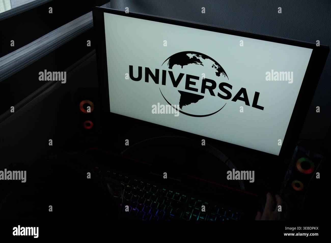 Il logo e l'icona del globo Universal Pictures vengono visualizzati su un monitor di un computer in un ufficio domestico buio Foto Stock