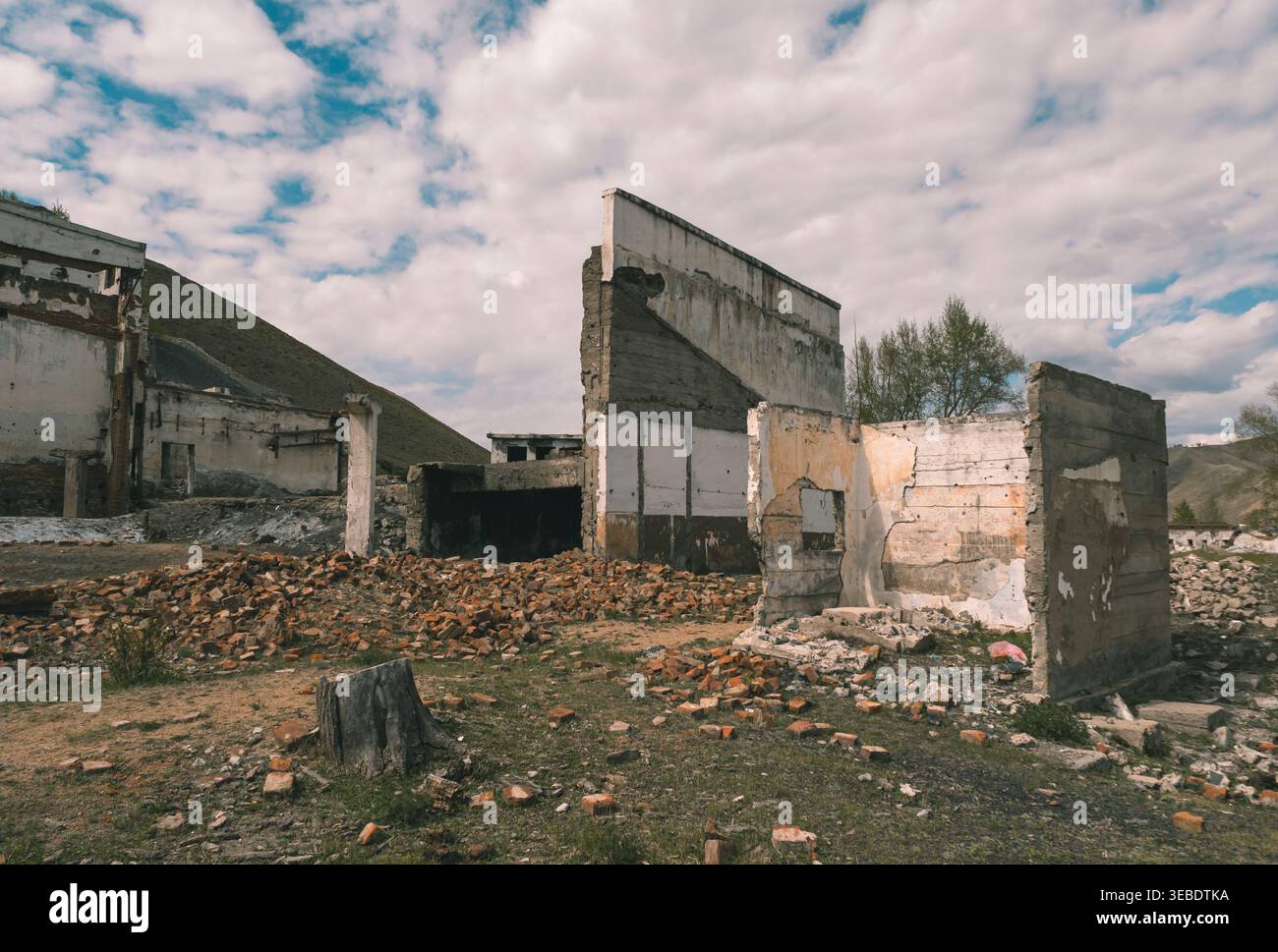 Edificio abbandonato con pareti in rovina e mattoni sparsi in un'area rurale in una giornata nuvolosa Foto Stock