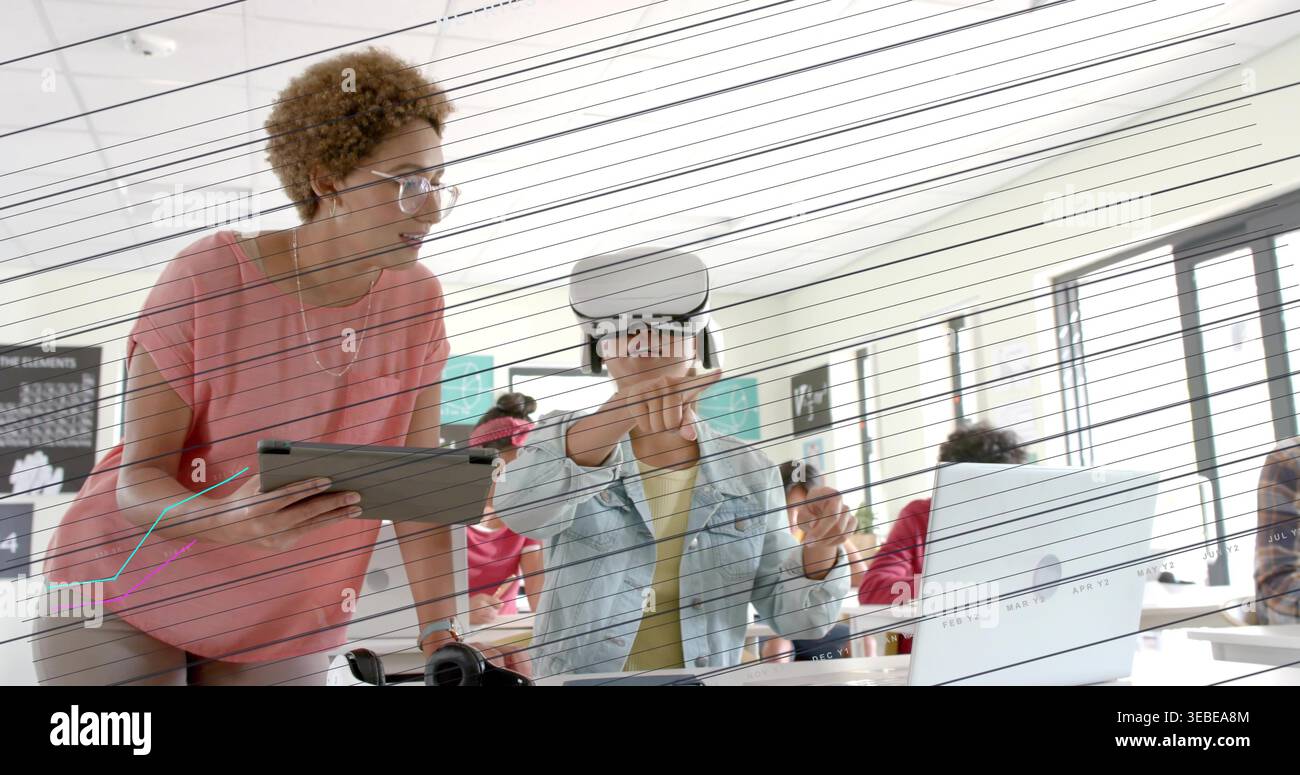 Raggiungere lo studente che indossa un visore VR bianco con l'insegnante che si appoggia a sinistra tenendo il tablet in laboratorio tecnologico Foto Stock