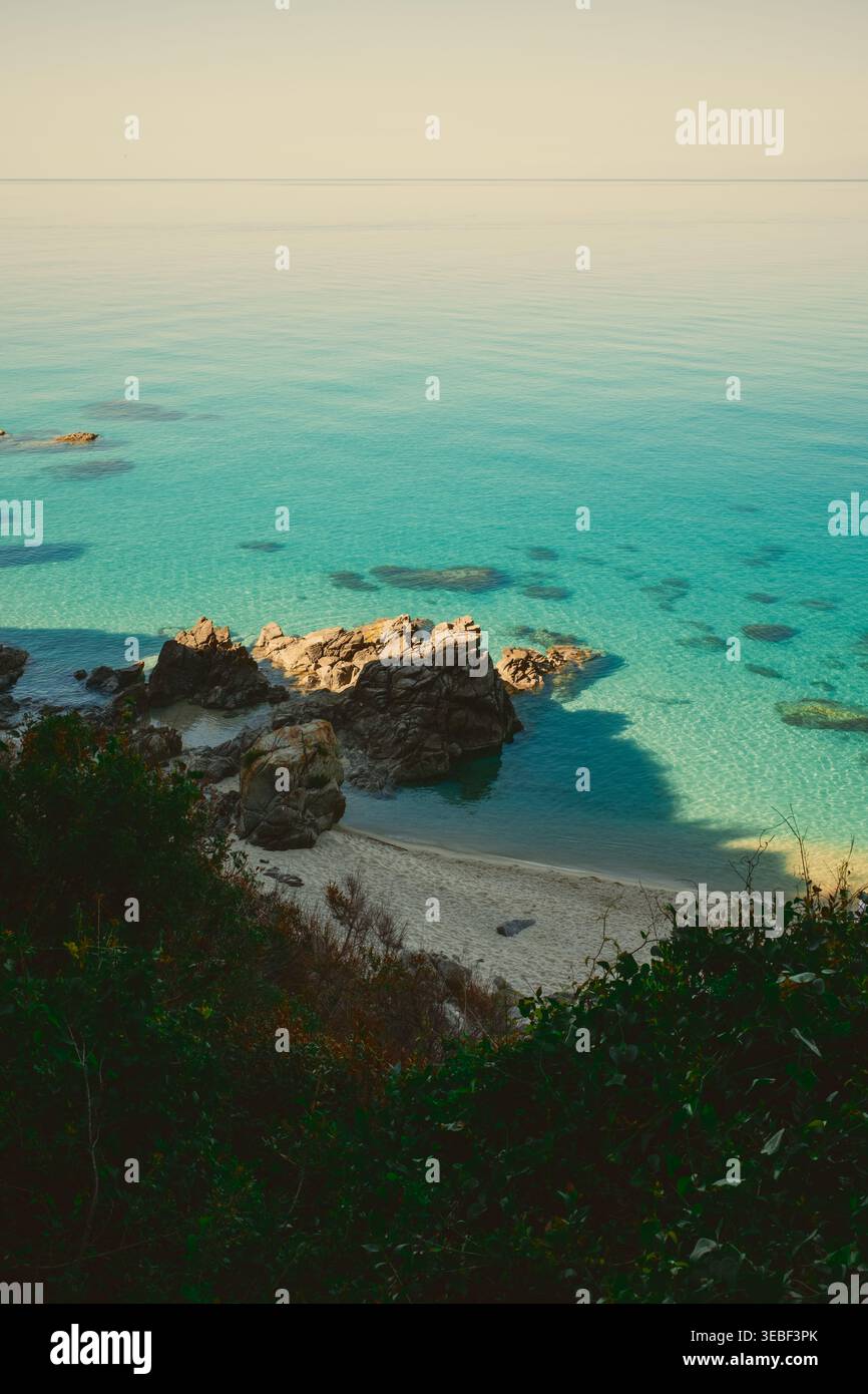 Baia illuminata dal sole con mare blu calmo Foto Stock