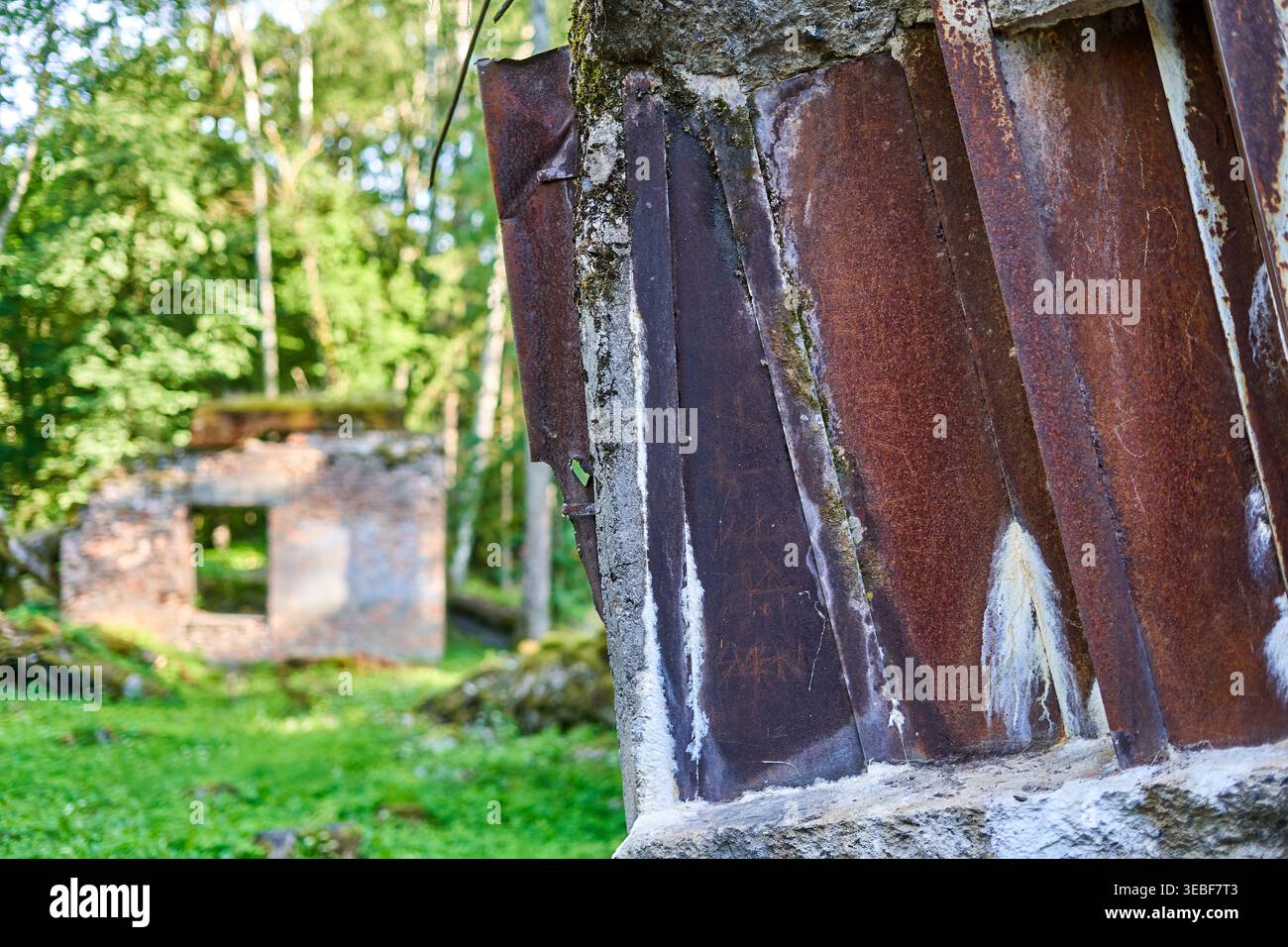 Dettaglio ravvicinato di lastre metalliche ondulate pesantemente arrugginite incastonate in cemento sgretolato, parte di una rovina architettonica abbandonata. Il tempo consumato Foto Stock