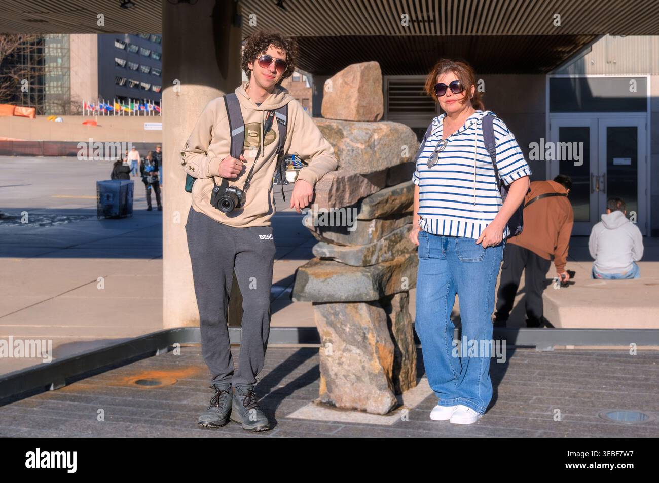 Due turisti che fingono da un Inuksuk delle prime Nazioni canadesi. Foto Stock