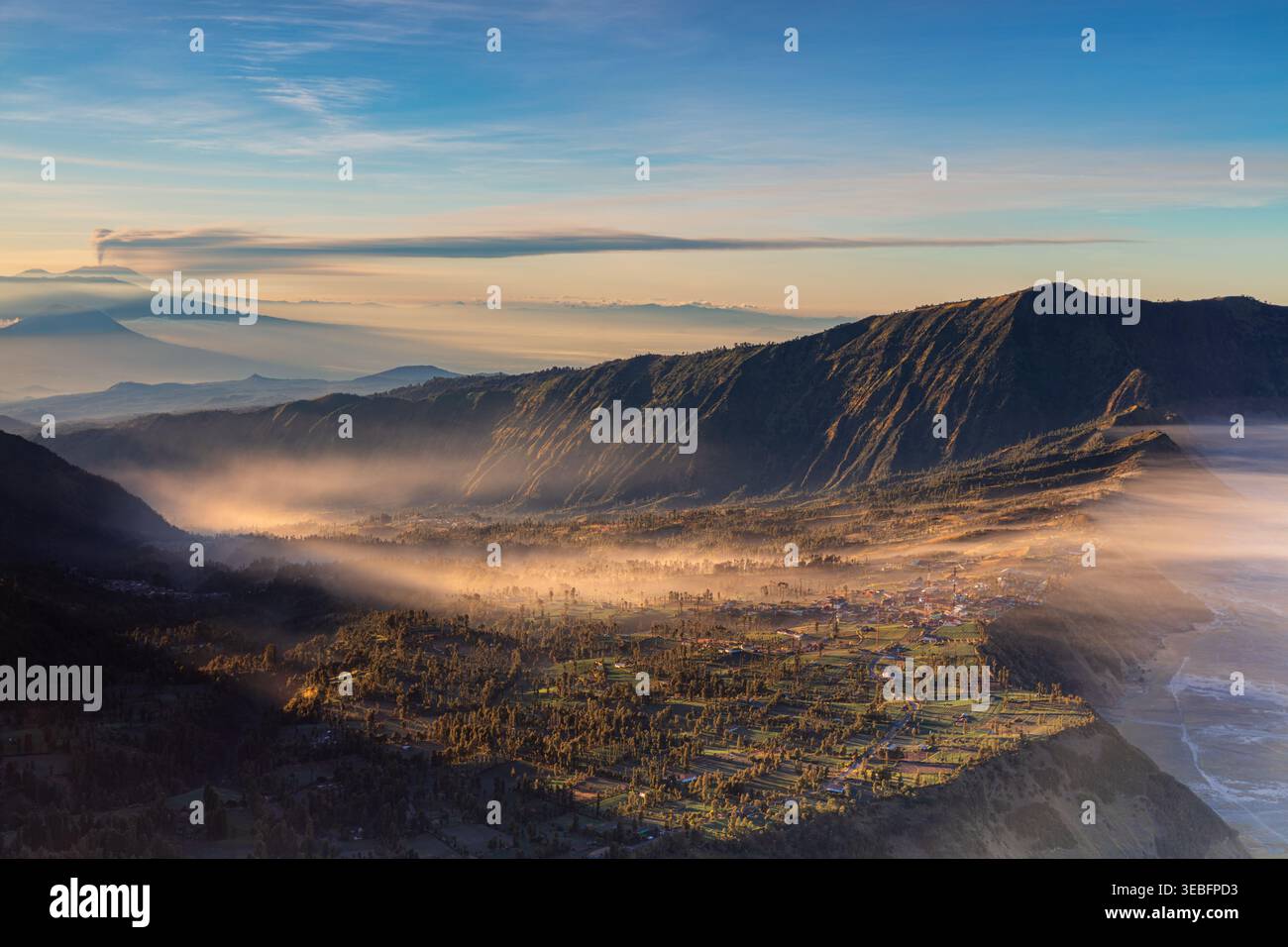 Alba dorata che illumina il nebbioso villaggio di Cemoro Lawang sul bordo dell'enorme caldera di Tengger vicino al Monte Bromo, Giava Orientale, Indonesia Foto Stock