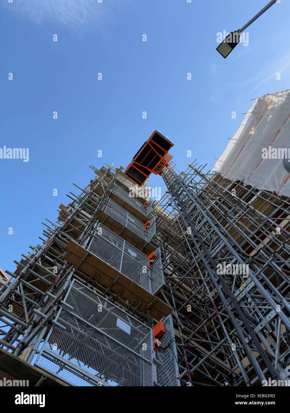 Alto ponteggio di costruzione con ascensore contro il cielo limpido Foto Stock